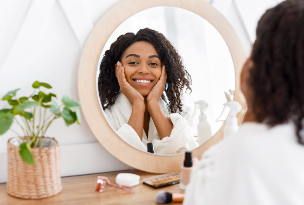 Black woman sitting at a vanity smiling.