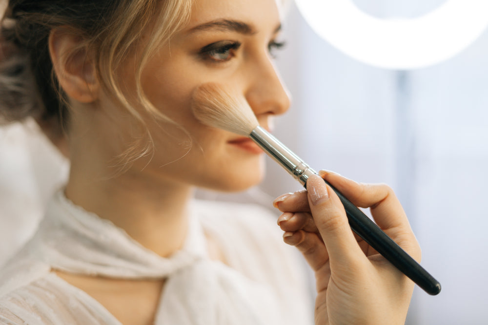 Woman applying makeup to her face using a makeup brush