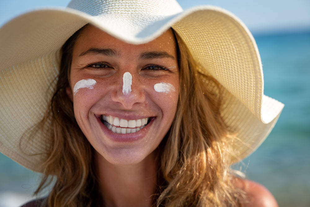 Image of a woman in a sunhat with sunscreen on her nose and cheek.