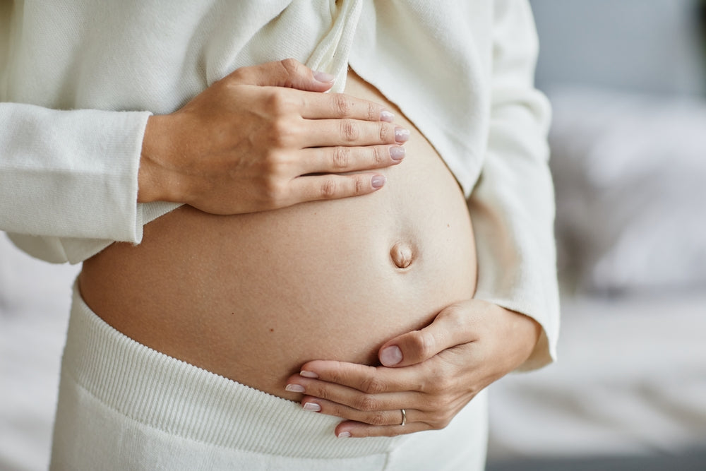 Close up of a pregnant woman holding her stomach.