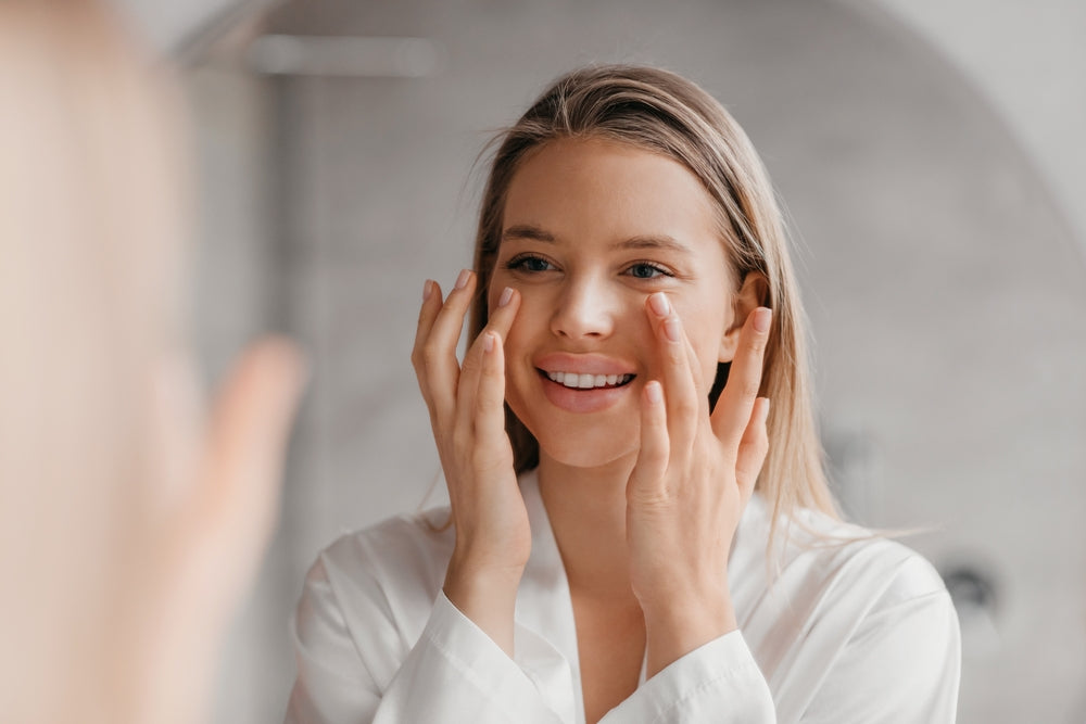 Blonde woman with youthful skin looking at her reflection.