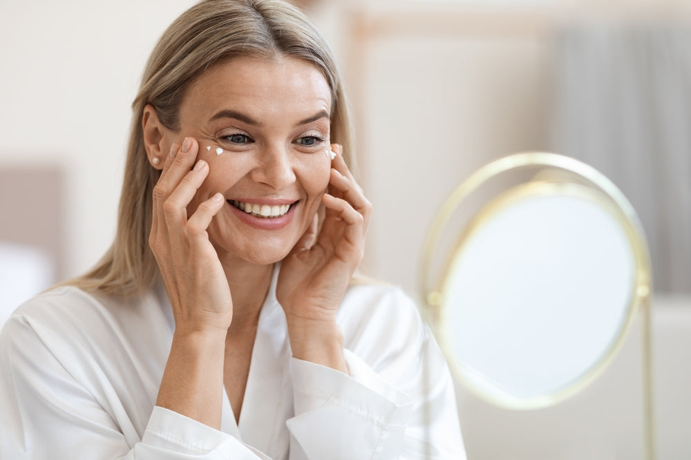 Woman moisturizing her face while looking at herself in the mirror