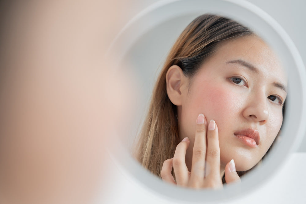 Woman looking at red skin in mirror.