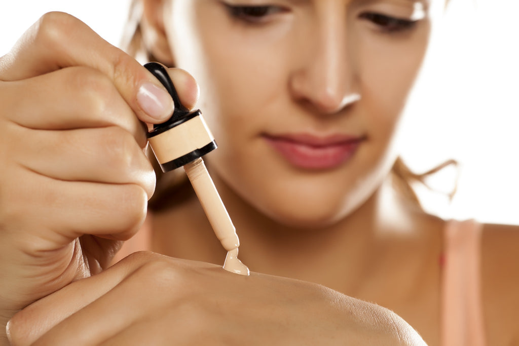 Woman putting liquid foundation onto her hand to color match 