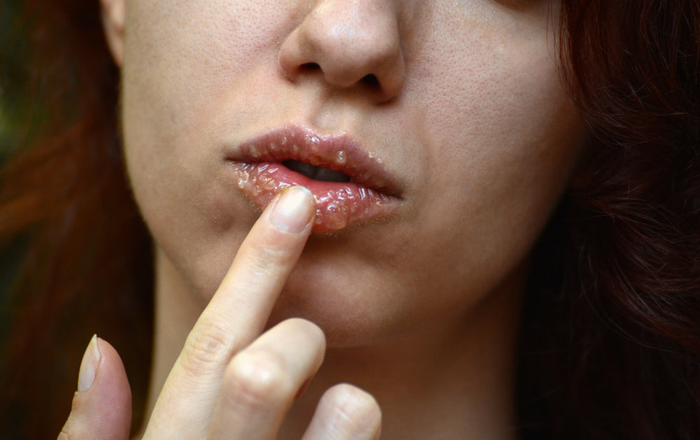 Close-up of woman rubbing an exfoliating scrub on her lip.