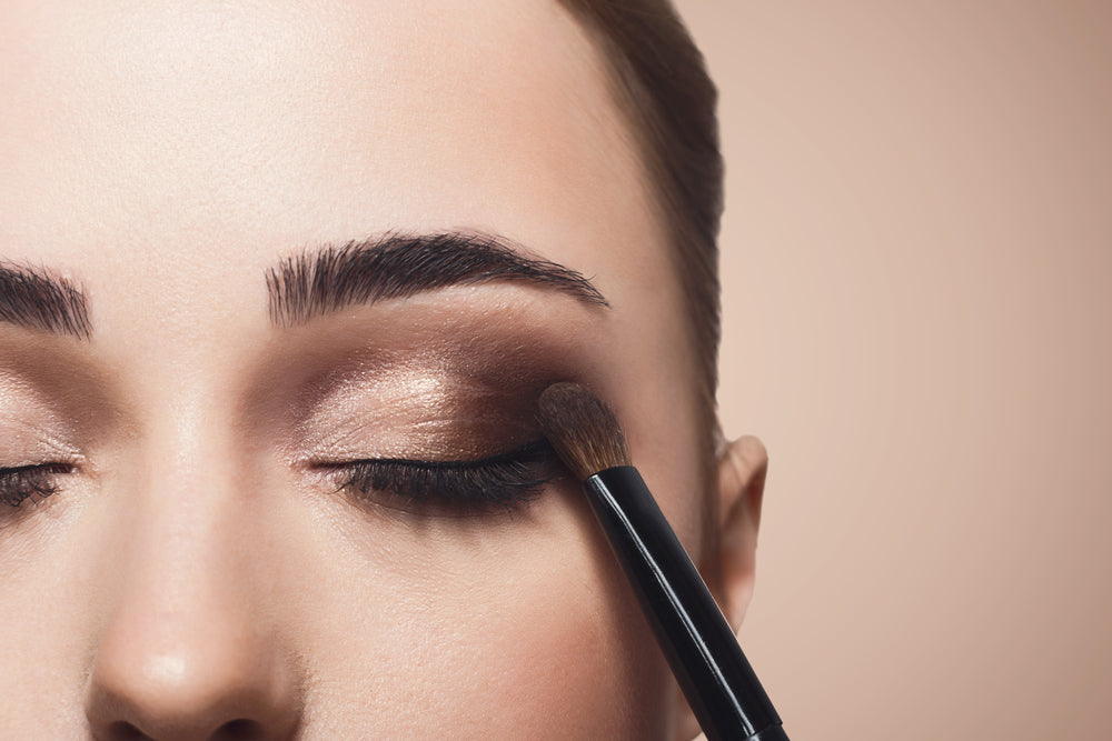 Woman applying eyeshadow to her eyelids as part of her makeup routine