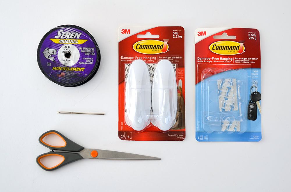 Materials to hang wall baskets: command hooks, fishing line, scissors, and sewing needle