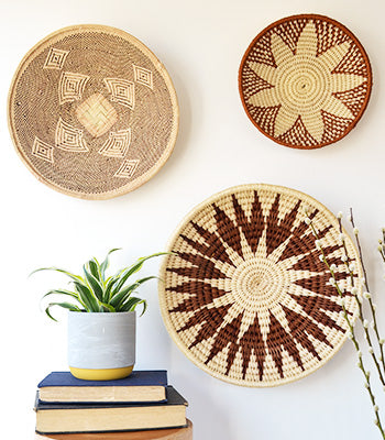 Binga basket and sisal baskets in a display of wall baskets, styled with books and plants