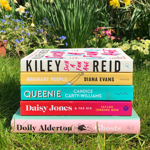 A stack of books from top to bottom: Such a Fun Age, Ordinary People, Queenie, Daisy Jones & The Six, Ghosts