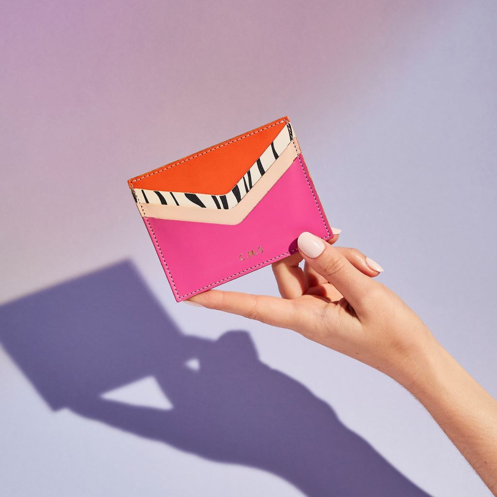 Sbri "Wild Thing" women's card holder in bright pink and orange leather with a zebra print accent, shown held in hand with personalised initials