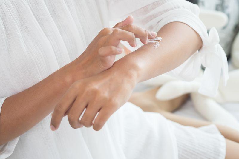 mujer aplicando crema en brazo