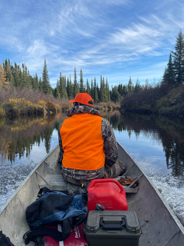 A moose hunter looks outwards from a traveling canoe as they meander down a narrow river