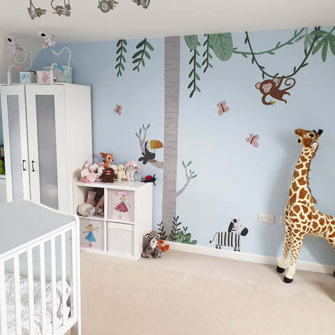 jungle themed bedroom with large plush giraffe and animal wall stickers