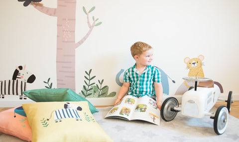 child reading a book in a children's room with scatter pillows