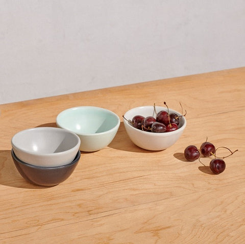 Four mini bowls in 4 colors on table with cherries