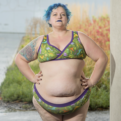 Model is standing outside wearing a green dinosaur print underwear set.