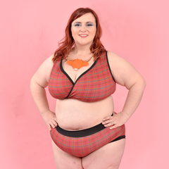 Model is wearing a red tartan underwear set with black trim. She's also wearing a large plastic highland cow necklace.