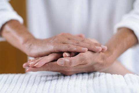 Zoom in of a Reiki practitioner holding the hand of a client in both of their hands giving reiki.