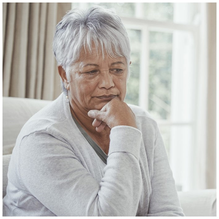 senior woman sitting on sofa thinking about how to talk to a loved one about incontinence