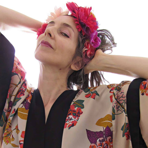 Alex Mitchell wearing floral kimono and flower crown feeling fab tilting head back with a knowing look at camera.