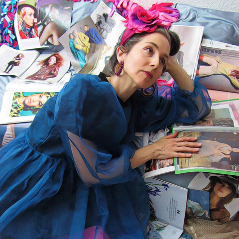 Alex Mitchell in a blue fancy dress and pink hairband surrounded by magazines dreaming about having fun with fashion.
