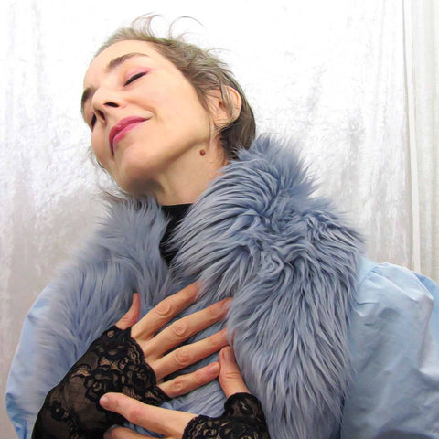 Alex Mitchell posing with a soft light blue imitation fur stole worn over the shoulders.