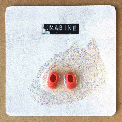 Square painting with little red shoes in a puddle of glitter on white background with word IMAGINE on top by Alex Mitchell.