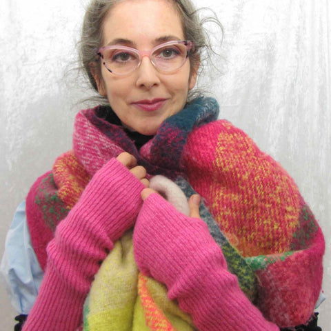 Alex Mitchell posing with a multicolor fuzzy blanket scarf worn over the shoulders.