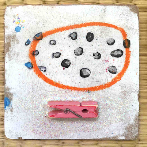 Square painting with black dots inside orange circle and pink clothes clip on white background by Alex Mitchell.