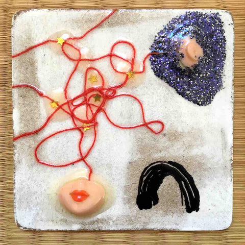 Square painting with doll parts, purple glitter puddle, and tiny gold stars on red thread by Alex Mitchell.