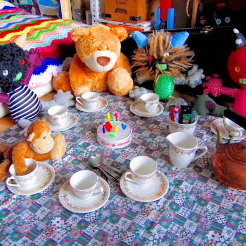 Colorful and funny group of stuffed animals sitting on a decked out picnic blanket ready for a tea party.