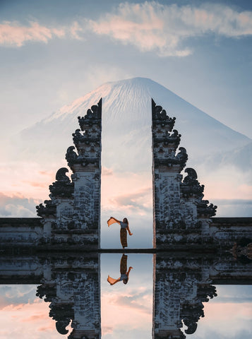 A spiritual traveler dances in the Candi Bentar gate of a Balinese temple