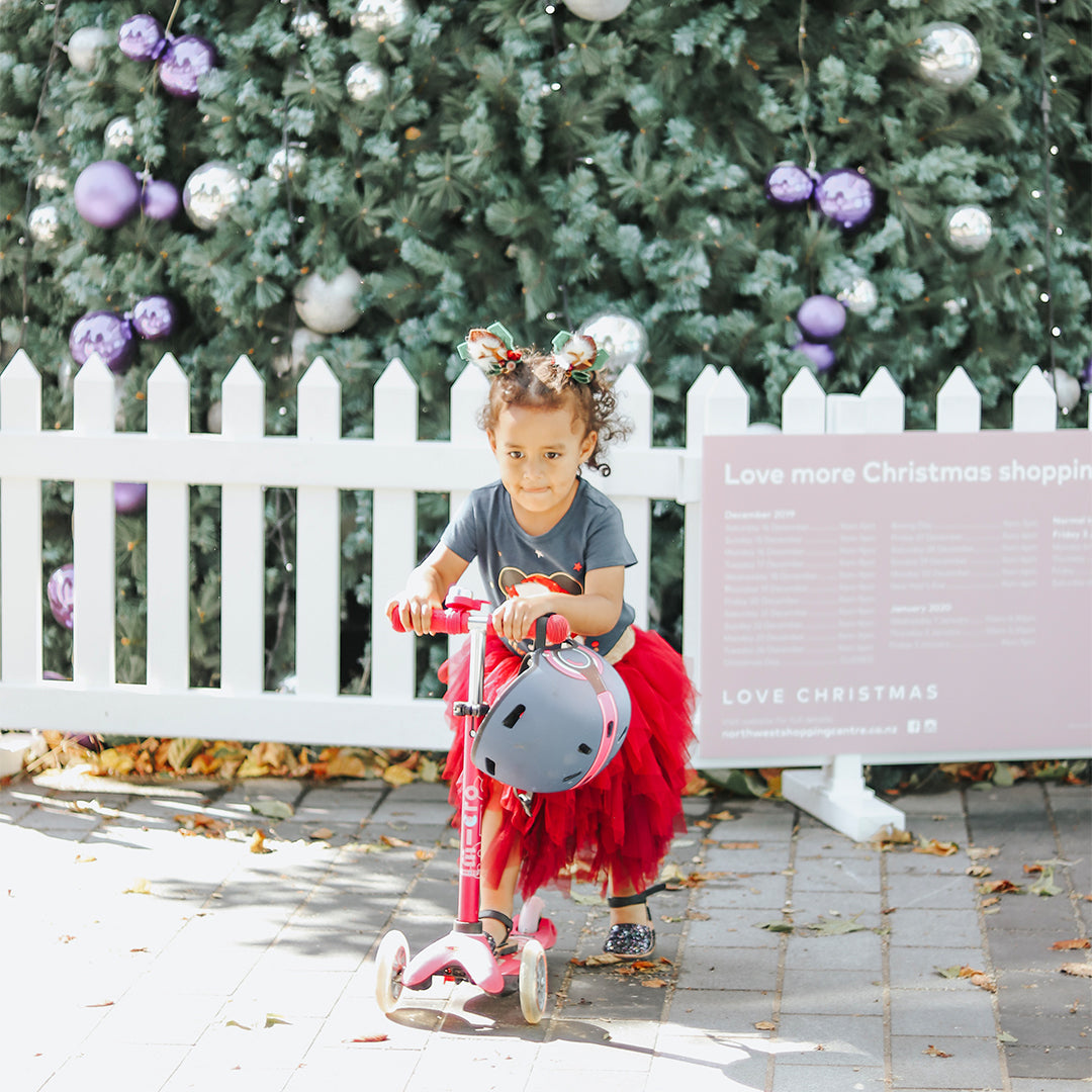 young girl on 3 wheel micro scooter in front of christmas tree