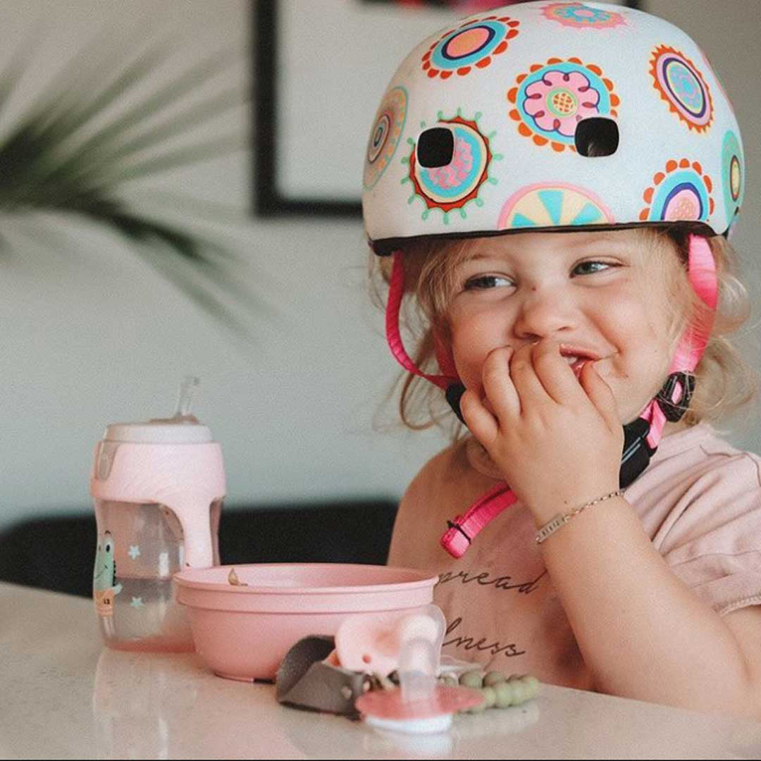 young girl eating at the breakfast bar in her micro scooters patterned helmet