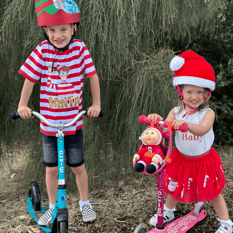 Jakey and Mia posing in Christmas costumes with their Micro Scooters