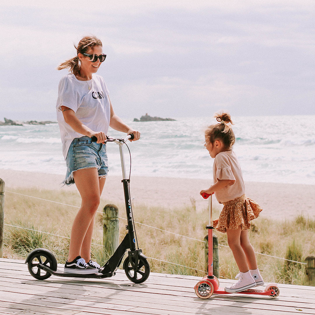 mum and daughter on their micro scooters at the beach