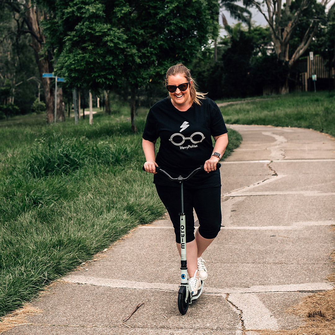 mum riding Micro Scooters 2 wheel adult scooter along a path