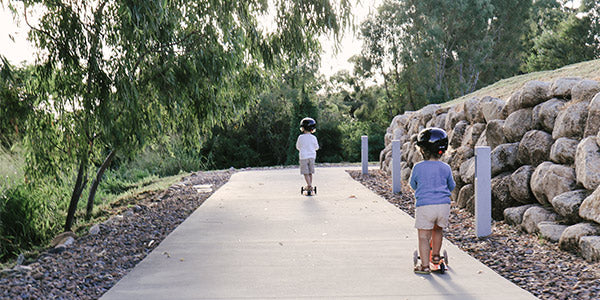 two kids scooting together on a path