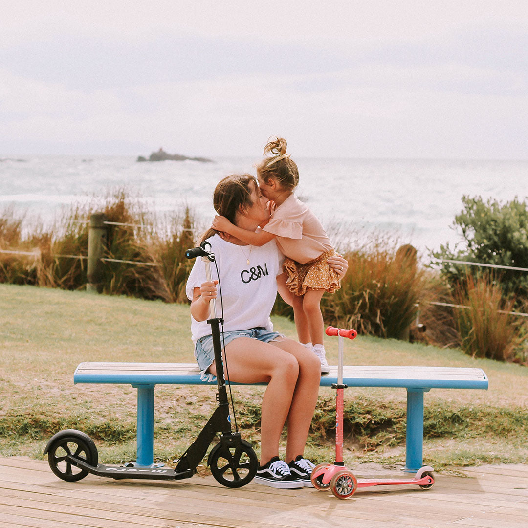 mum and daughter hugging with their scooters at beach