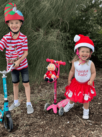 Jakey and Mia posing in Christmas outfits with their Micro Scooters