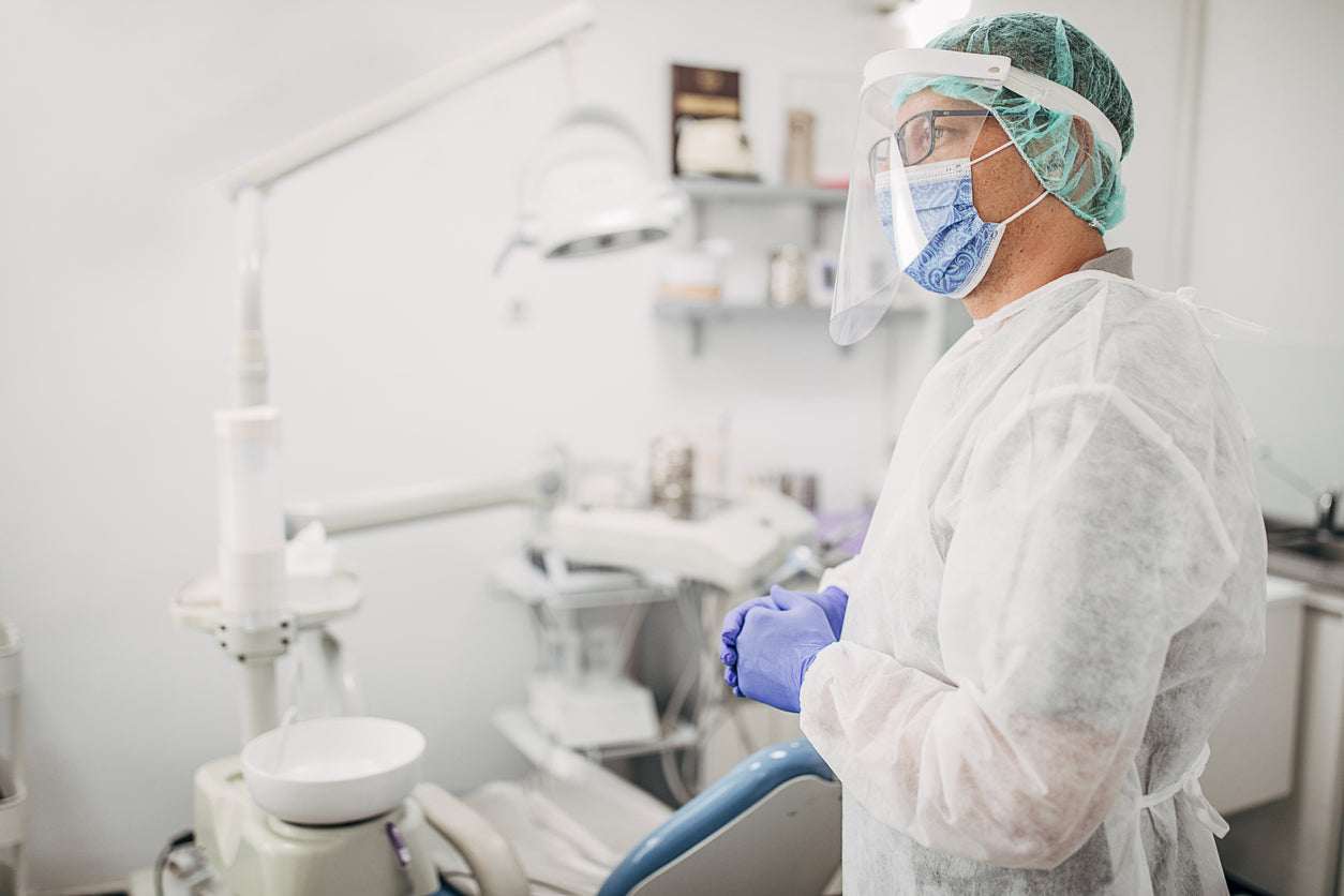 Male dentist working and wearing PPE for dental infection control.