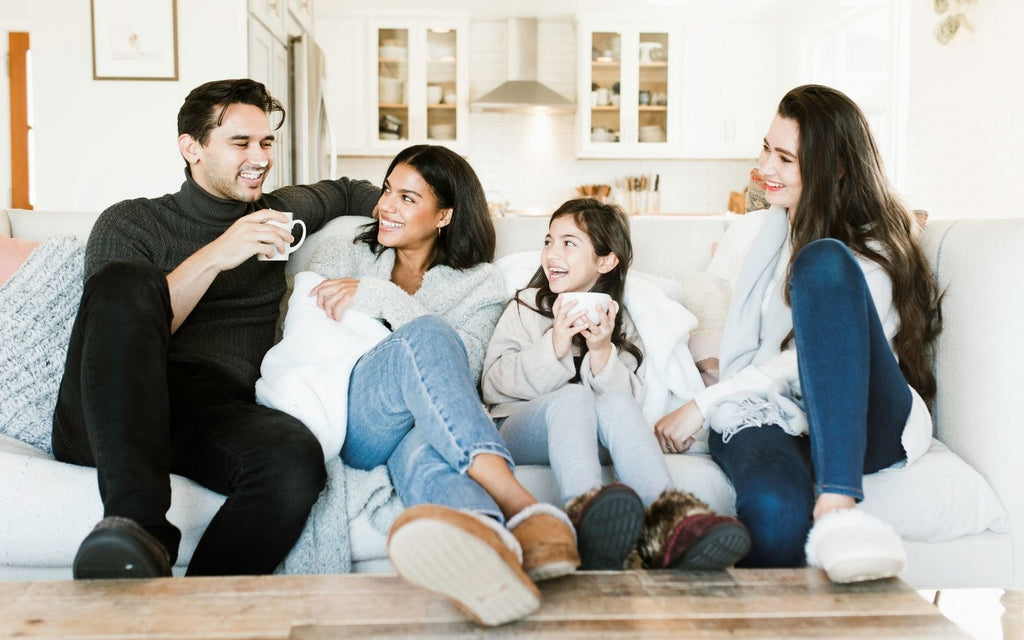 Family sitting on a sofa in their Isotoner slippers, Laughing and enjoying each other's company