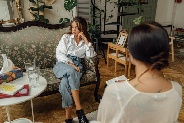 A woman sitting on a couch across from a therapist