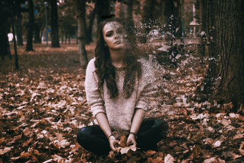 Anxious girl sitting in pile of leaves 