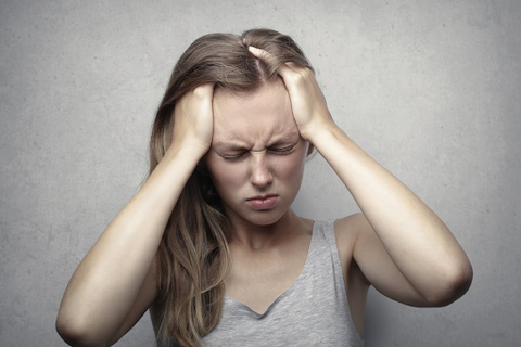 A woman holding her head in pain.