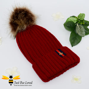 Wine ribbed knit hat featuring a faux fur pom pom with embroidered bumblebee tab on rim