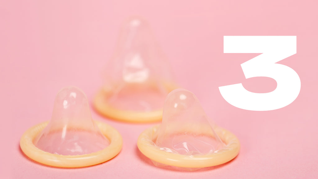 Trois condoms ouverts sur fond rose avec le chiffre 3 écrit en blanc à côté.