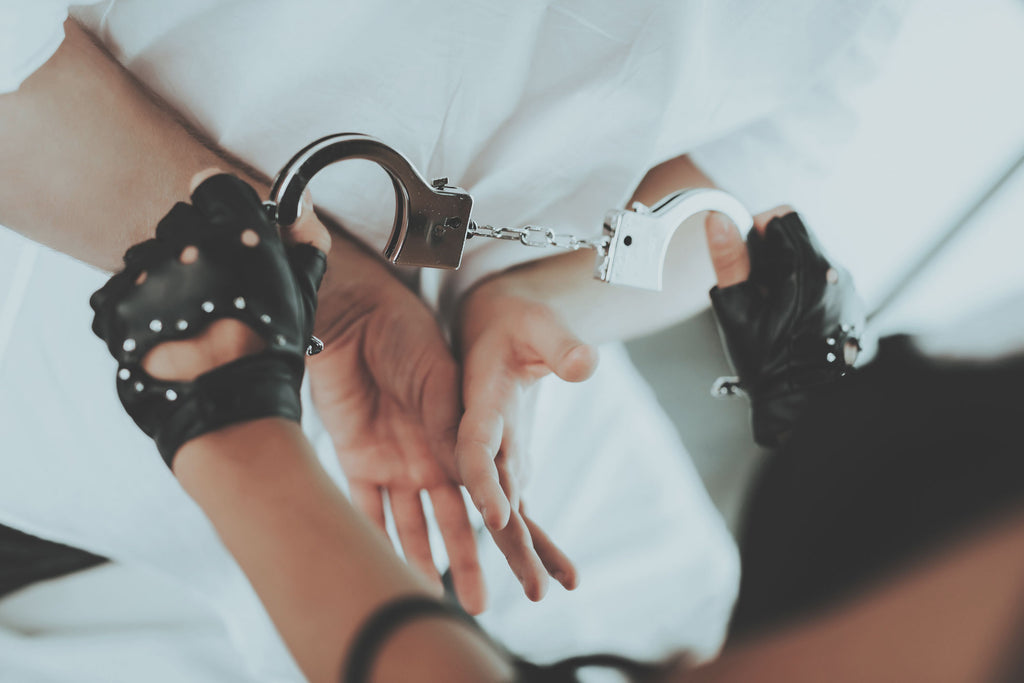 One partner in leather gloves placing handcuffs on their suitor.