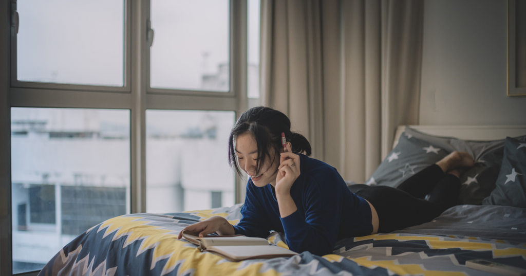 Une fille lit ses notes dans son lit avant de parler avec ses parents de santé sexuelle. 