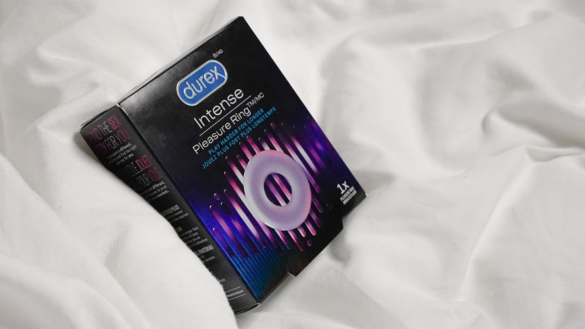 Durex Pleasure Ring packaging standing upright on white bed sheets.